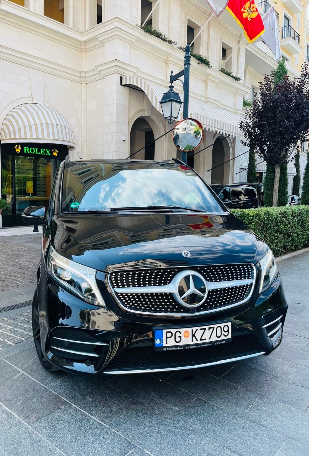 Black Mercedes-Benz van parked in front of a Rolex store in a luxury shopping district