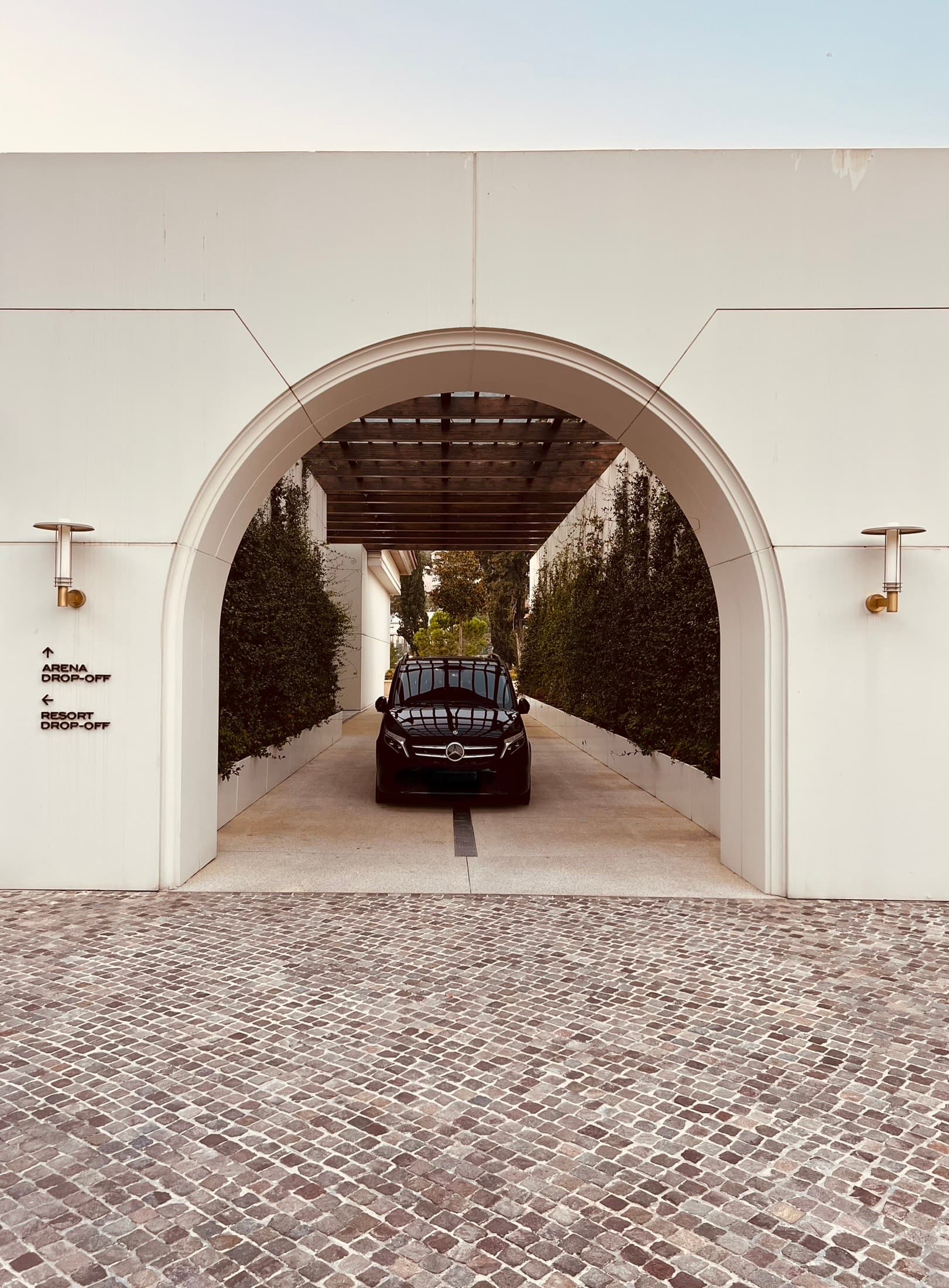 Black Mercedes-Benz van parked under an archway at a resort drop-off area