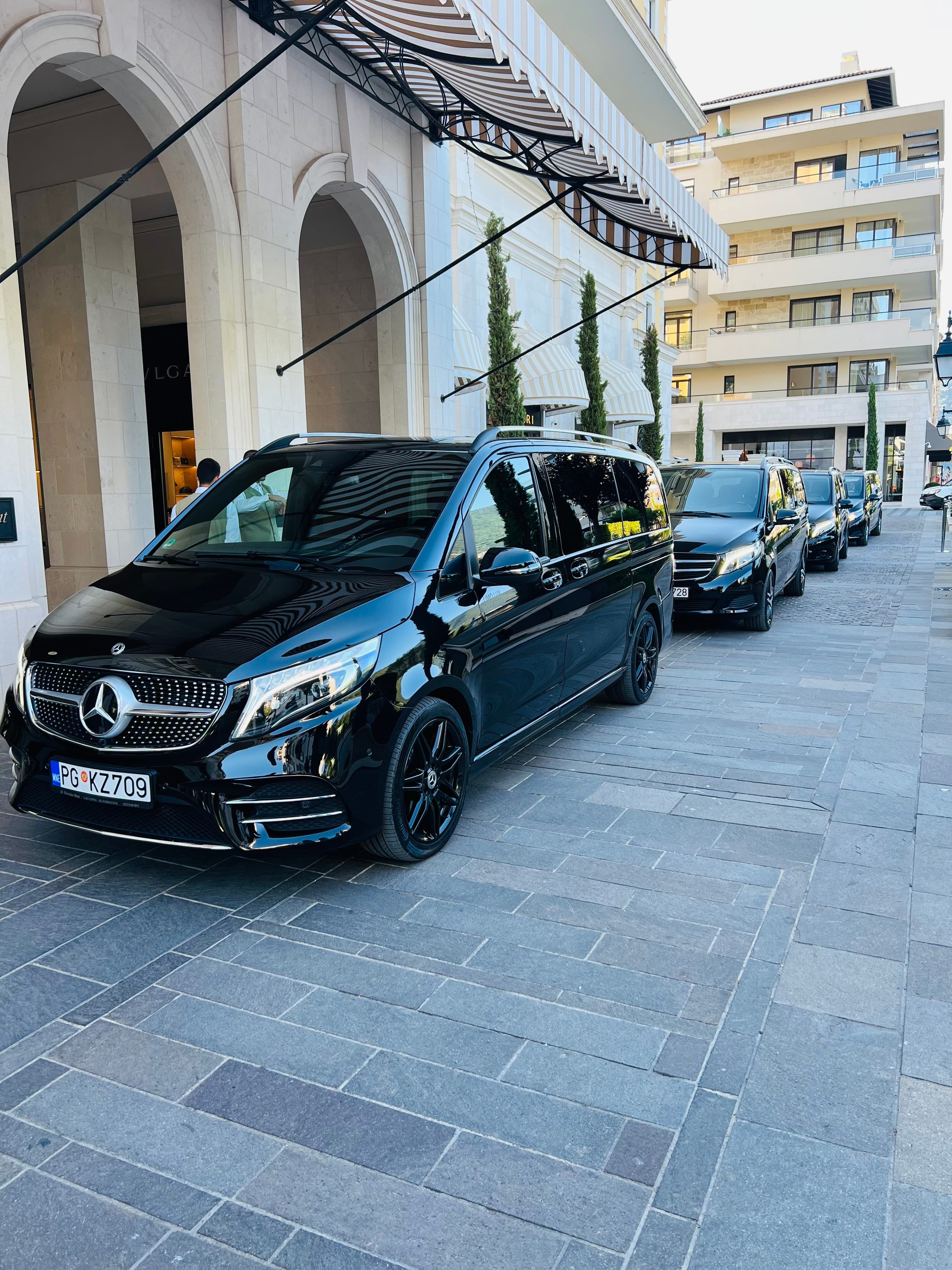 Black Mercedes-Benz vans parked in front of a luxury hotel entrance