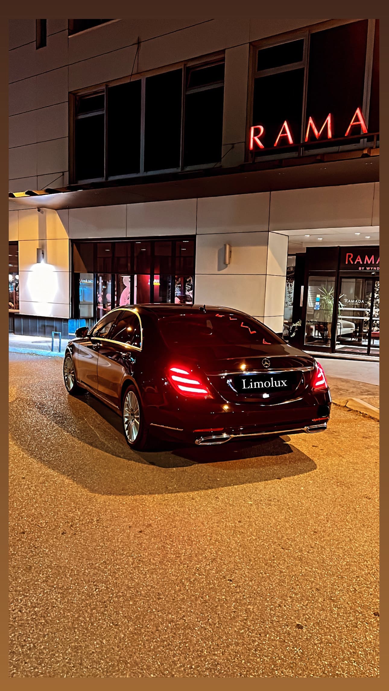 Rear view of a black Mercedes-Benz sedan at night in front of a hotel